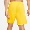 Ein Mann trägt gelbe Shorts von der Seite, eine Hand in der Tasche.