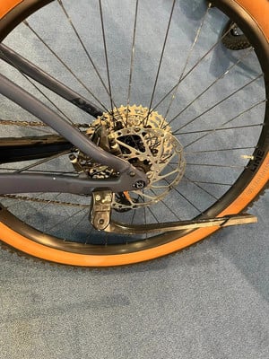 Beschädigtes Hinterrad eines Fahrrads mit verbogenem Felgenhorn und orangefarbenem Reifen.