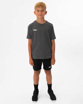 Ein Junge in einem dunkelgrauen T-Shirt und schwarzer Hose steht vor weißem Hintergrund. Ein Junge in einem dunkelgrauen T-Shirt und schwarzer Hose steht vor weißem Hintergrund.