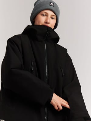 Junger Mensch in schwarzer Jacke und grauem Hut mit Logo.