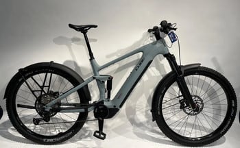Ein graues Cube E-Bike mit Federung und Schutzblechen steht vor weißem Hintergrund.