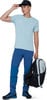 Ein Mann in blauer Hose, hellblauem T-Shirt und schwarzer Kappe hält einen Rucksack.
