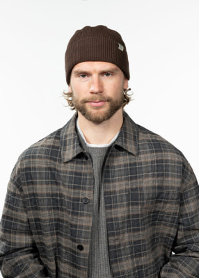 Ein Mann mit brauner Mütze und kariertem Hemd über einem grauen Pullover. Ein Mann mit brauner Mütze und kariertem Hemd über einem grauen Pullover.