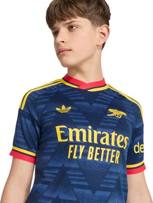 Junge in dunkelblauem Fußballtrikot mit gelben und roten Details. Junge in dunkelblauem Fußballtrikot mit gelben und roten Details.