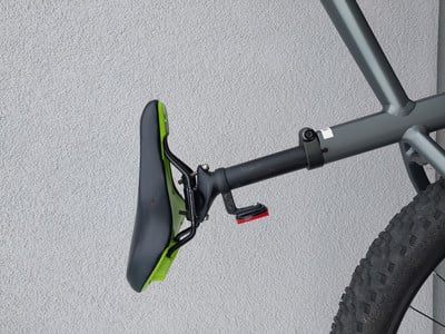 Ein Fahrradsattel mit einem roten Reflektor an der Sattelstütze.