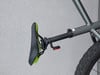 Ein Fahrradsattel mit einem roten Reflektor an der Sattelstütze.