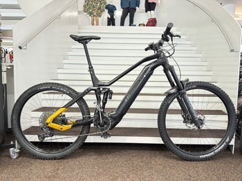 Schwarzes E-Bike mit Federung auf einer Treppe, gelbe Rahmendetails.