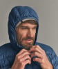 Ein Mann schließt eine dunkelblaue Daunenjacke mit Kapuze.