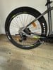 Hinterrad eines Mountainbikes mit Maxxis-Reifen und Shimano-Schaltwerk auf Holzboden.