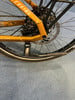 Goldenes Fahrrad mit Scheibenbremsen und Ständer auf blauem Teppich.