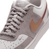 Szürke Nike cipő részletes képe arany pipával és rózsaszín csíkkal.