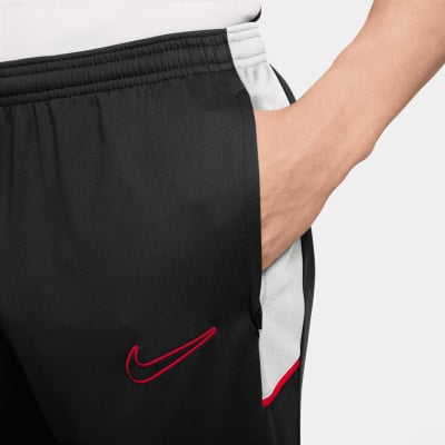 Schwarze Trainingshose mit rotem Nike-Logo und weißen Streifen. Schwarze Trainingshose mit rotem Nike-Logo und weißen Streifen.