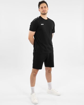 Ein Mann in einem schwarzen T-Shirt und Shorts steht vor einem weißen Hintergrund.