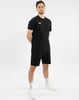 Ein Mann in einem schwarzen T-Shirt und Shorts steht vor einem weißen Hintergrund.