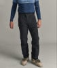 Mann in schwarzer Skihose und blauem Oberteil mit Skischuhen.