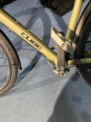 Grünes Cube-Fahrrad mit Logo auf dem Rahmen und Pedal auf blauem Teppich.