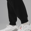 Nahaufnahme von Beinen in schwarzer Jogginghose und weißen Turnschuhen mit rotem Logo.