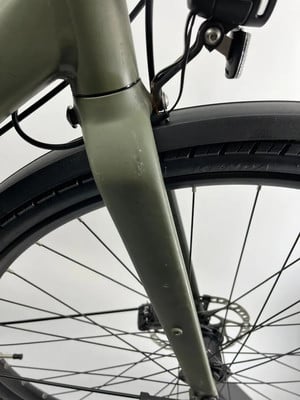 Detail der vorderen Gabel eines grünen Fahrrads mit Schutzblech und Licht.