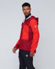 Ein Mann in einer roten Kapuzenjacke und schwarzen Hosen mit Logo.