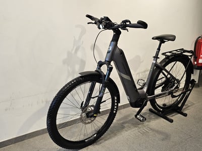 Graues E-Bike mit Federung und Gepäckträger an der Wand. Graues E-Bike mit Federung und Gepäckträger an der Wand.