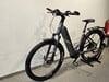 Graues E-Bike mit Federung und Gepäckträger an der Wand.
