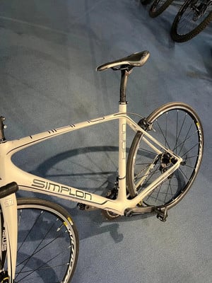 Ein weißes Simplon Rennrad mit Sattel und Hinterrad ist sichtbar. Ein weißes Simplon Rennrad mit Sattel und Hinterrad ist sichtbar.