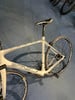 Ein weißes Simplon Rennrad mit Sattel und Hinterrad ist sichtbar.
