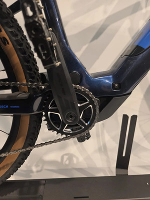 Detail eines E-Bike-Rahmens mit Kurbeln und Kette auf einem Ständer. Detail eines E-Bike-Rahmens mit Kurbeln und Kette auf einem Ständer.