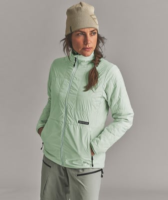 Eine Frau in einer Daunenjacke und Mütze posiert vor grauem Hintergrund. Eine Frau in einer Daunenjacke und Mütze posiert vor grauem Hintergrund.
