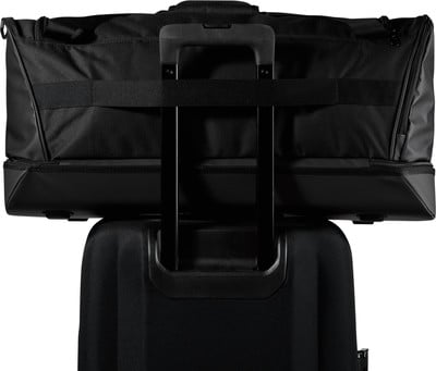 Schwarze Reisetasche, befestigt am ausziehbaren Griff eines Koffers. Schwarze Reisetasche, befestigt am ausziehbaren Griff eines Koffers.