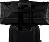 Schwarze Reisetasche, befestigt am ausziehbaren Griff eines Koffers.