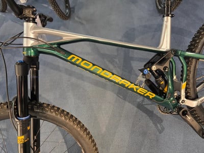 Ein Mondraker Mountainbike mit Dämpfer und grünem Rahmen mit gelbem Schriftzug. Ein Mondraker Mountainbike mit Dämpfer und grünem Rahmen mit gelbem Schriftzug.