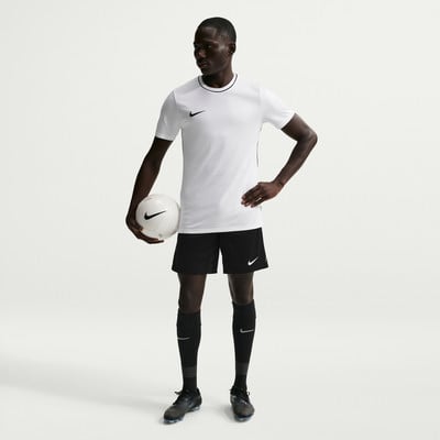 Ein Mann im weißen Fußballtrikot und schwarzer Hose hält einen Ball. Ein Mann im weißen Fußballtrikot und schwarzer Hose hält einen Ball.