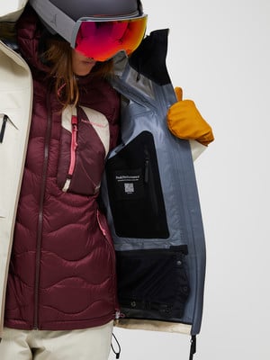 Skifahrerin in Jacke mit Weste und Brille, Detail der Innentasche. Skifahrerin in Jacke mit Weste und Brille, Detail der Innentasche.