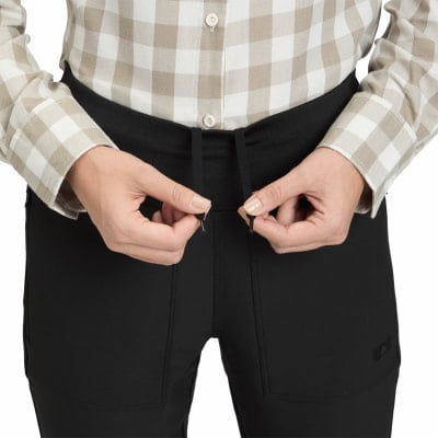Eine Frau zieht die Kordel ihrer schwarzen Hose fest, sie trägt ein kariertes Hemd. Eine Frau zieht die Kordel ihrer schwarzen Hose fest, sie trägt ein kariertes Hemd.