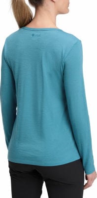 Frau in einem türkisfarbenen Langarmshirt und schwarzer Hose vor weißem Hintergrund. Frau in einem türkisfarbenen Langarmshirt und schwarzer Hose vor weißem Hintergrund.