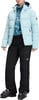 Person in einer Daunenjacke und Skihose mit Skischuhen.