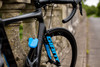 Ein blaues Fahrradschloss mit Stahlkabel ist am Fahrradrahmen befestigt.