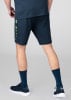 Mann in dunkelblauen Shorts und Socken mit Turnschuhen.