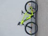 Ein grünes E-Bike lehnt an einer grauen Wand, Nahaufnahme von Rahmen und Rädern.