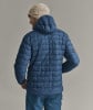 Ein Mann in einer blauen Daunenjacke und einer cremefarbenen Mütze mit Logo.