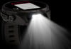 Schwarze Smartwatch mit eingeschalteter LED und Lichtstrahlen.