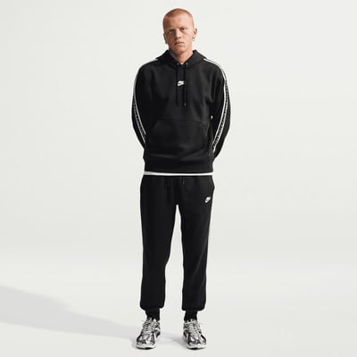 Ein Mann in schwarzer Nike-Kleidung mit weißen Streifen an Ärmeln und Hosen. Ein Mann in schwarzer Nike-Kleidung mit weißen Streifen an Ärmeln und Hosen.