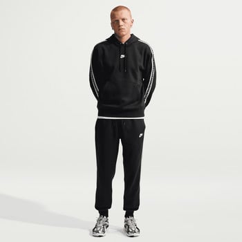 Ein Mann in schwarzer Nike-Kleidung mit weißen Streifen an Ärmeln und Hosen.