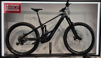 Schwarzes Orbea Mountain-E-Bike auf einem Ständer mit Werbeschild.