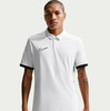Ein Mann in einem weißen Poloshirt mit schwarzem Nike-Logo und schwarzen Ärmelbündchen.