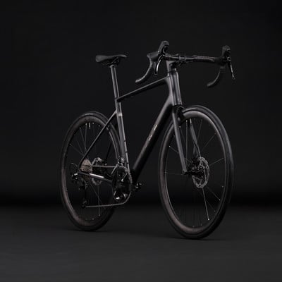 Ein schwarzes Carbon-Gravelbike mit Scheibenbremsen auf dunklem Hintergrund. Ein schwarzes Carbon-Gravelbike mit Scheibenbremsen auf dunklem Hintergrund.