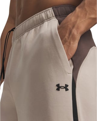 Ein Mann hat seine Hände in den Taschen einer beigen Jogginghose mit braunen Einsätzen. Ein Mann hat seine Hände in den Taschen einer beigen Jogginghose mit braunen Einsätzen.