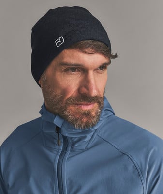 Ein Mann in einer dunklen Mütze und blauer Kapuzenjacke schaut nach rechts.
