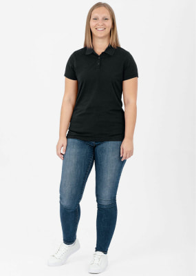 Eine Frau in einem schwarzen Poloshirt und Jeans steht vor weißem Hintergrund. Eine Frau in einem schwarzen Poloshirt und Jeans steht vor weißem Hintergrund.
